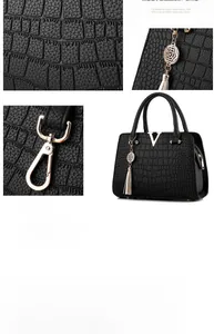 Detail of black crocodile pattern handbag with golden hardware V-logo and tassel charm
