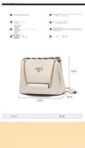 Detailed view showing dimensions 23x10x18cm of beige crossbody bag with gold bow charm