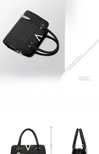 Detail of black crocodile pattern handbag showing golden V decoration and 11cm handle