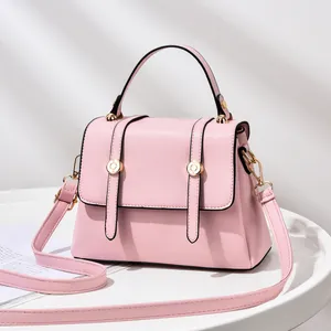 Close-up of pink crossbody bag with gold buckle hardware and elegant vertical straps