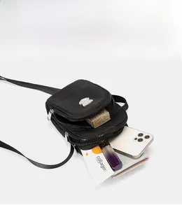 Dettagli di una borsa a tracolla nera in nylon con vari scomparti con cerniera