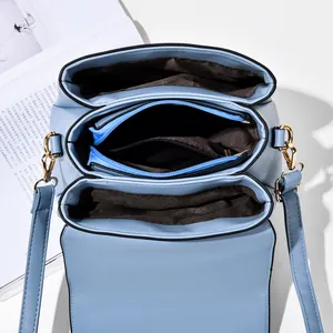 Detailed top view of light blue leather handbag showing three inner compartments and gold hooks