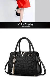 Detail of black crocodile pattern handbag with gold V logo and metal fringe tassel