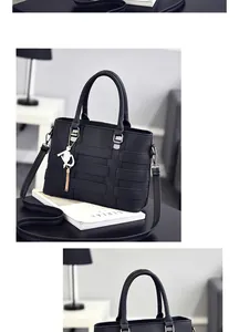 Detail of black pebbled leather handbag featuring woven texture and a gold cat charm
