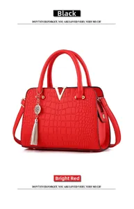 Detailed close-up of bright red crocodile texture leather handbag with silver V-logo
