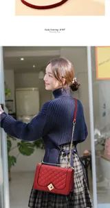 Détail d'un sac bandoulière rouge matelassé avec chaîne dorée porté par un mannequin