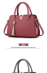 Detail of dusty rose crocodile embossed leather handbag with gold V buckle and tassel