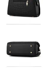 Detail view showing back zipper pocket and bottom metal feet of black crocodile tote bag