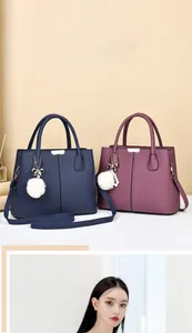 Détail d'un sac à main texturé avec un nœud en métal et un pompon décoratif