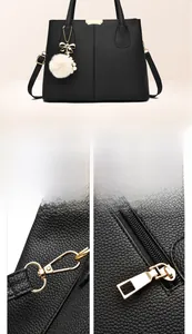 Détail de la quincaillerie dorée et charm pompon sur sac à main en cuir noir