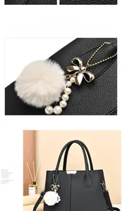 Détail d'un bijou de sac avec pompon blanc, perles et nœud doré sur cuir noir grainé