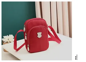 Dettaglio della borsa a tracolla in nylon rosso con tre scomparti a cerniera