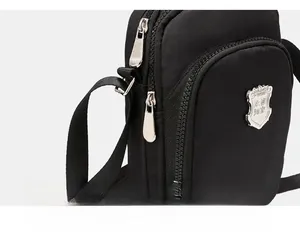 Dettaglio della cerniera in metallo e dell'emblema d'argento sulla borsa in nylon nero