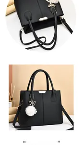 Détail du sac à main en cuir noir avec garniture dorée et pendentif en peluche blanc