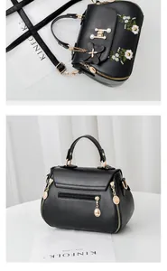 Detail of black embroidered handbag with floral patterns and gold metal hardware