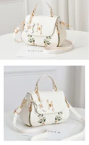 Detailed view of white floral embroidered bag with pearls and butterfly charm decoration