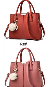 Détail du sac à main à motif litchi avec pendentif boule en fourrure et nœud en rouge et rose