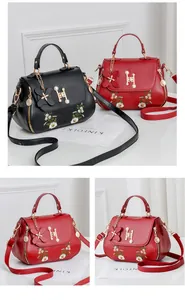 Detail of floral embroidery and pearl H-lock on black and red crossbody bags