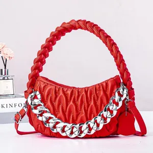 Close-up of red ruched leather handbag featuring woven handle and chunky silver chain