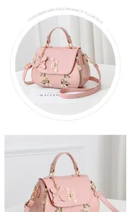 Detail view of pink crossbody bag with daisy embroidery and pearl hardware ornament