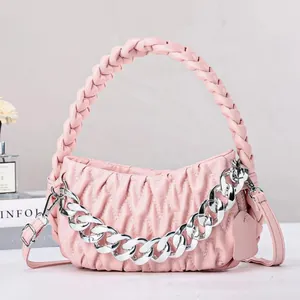 Detail of light pink pleated handbag with woven handle and silver chain accessory