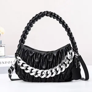 Close-up of black pleated cloud bag with chunky silver chain and woven handle detail