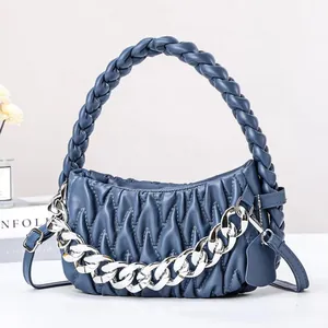 Detail of navy blue ruched leather handbag with woven handle and silver chain strap
