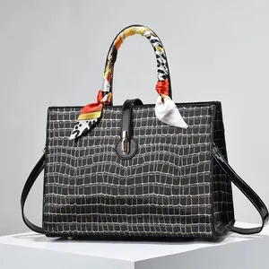 Detail of black crocodile texture handbag with golden buckle and colorful silk scarf wrap
