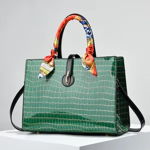 Dark green crocodile pattern handbag with gold clasp and decorative silk scarf accents