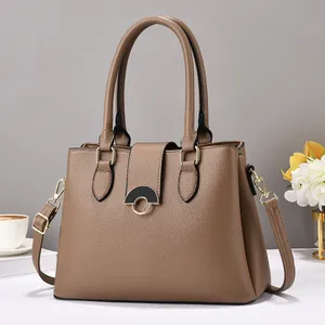 Detail view of brown pebbled leather handbag with elegant half-round gold-toned metal buckle
