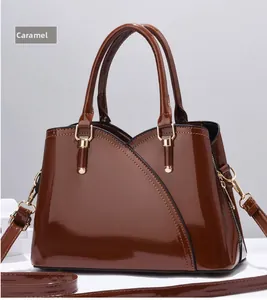 Dettaglio macro di borsa in pelle verniciata caramello con hardware in metallo dorato