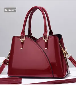 Dettaglio borsa in pelle verniciata rosso vino con finiture dorate e tracolla rimovibile