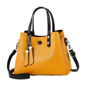 Fashionable mustard yellow PU leather handbag with black straps and silver rivets