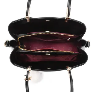 Interior of black faux leather handbag featuring burgundy floral lining and triple compartment