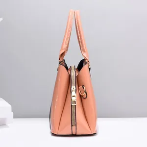 Dettaglio della borsa in pelle verniciata lucida con hardware dorato e struttura a pieghe