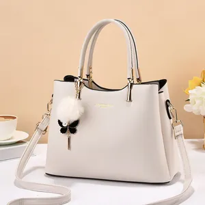 Cream white leather handbag with plush fur ball charm and detachable shoulder strap