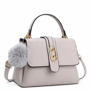 Light gray pebbled leather handbag with gold clasp and fur ball charm on white background