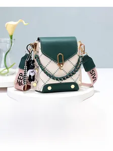Detail of green quilted mini phone bag with golden lock and bear charm