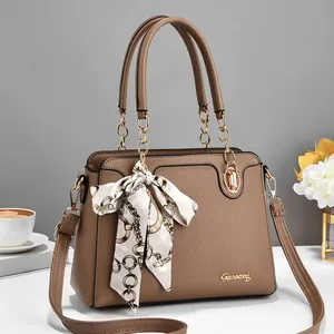 Brown lychee texture handbag with gold chain handles and scarf on a table