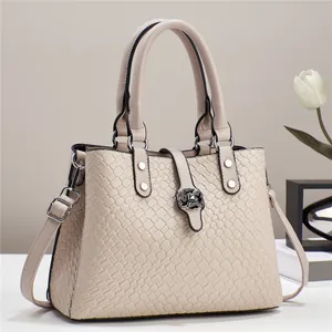 Detail of beige woven texture tote bag featuring a chic black floral metal clasp