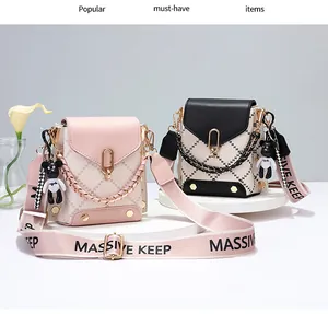 Detail of quilted mini crossbody bag with wide logo strap and bear charm accessory