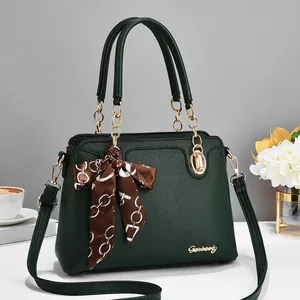 Elegant dark green lychee leather handbag with golden hardware and decorative silk scarf
