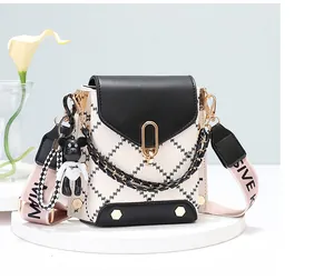 Detail of a white quilted crossbody bag with black trim and a cute panda pendant