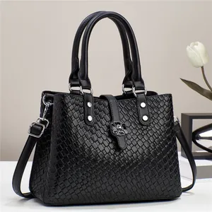 Close-up of black woven texture handbag with silver flower metal clasp and dual handles