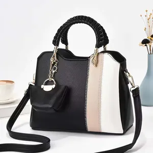 Detail der Farbmix-Lederhandtasche mit gewebtem Griff und passendem Mini-Taschenanhänger