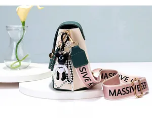 Side view of cream and green crossbody bag with a pink strap and a cute bear charm