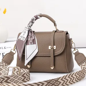 Sac à main en cuir marron avec foulard décoratif et bandoulière tissée à motifs géométriques
