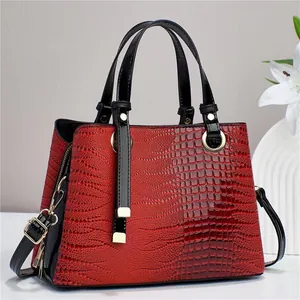 Deep red crocodile embossed handbag with black handles and gold hardware on a display stand