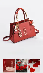 Macro detail of red leather handbag with silk scarf handle and golden leaf pendant
