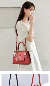Detail of burgundy large handbag with lychee texture, silk scarf and leaf pendant